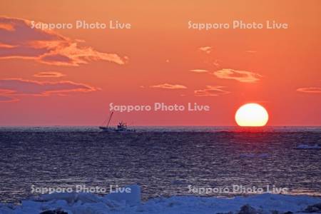 朝日とホタテ漁船と流氷