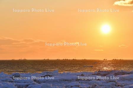朝日とホタテ漁船と流氷