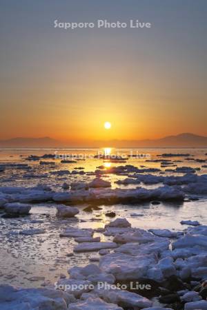 オホーツク海の日の出と流氷と海別岳（右）