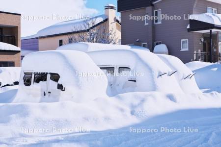大雪で埋もれた車と道