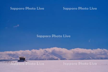 赤い屋根の小屋と十勝岳連峰