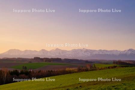 丘と十勝岳連峰の朝焼け